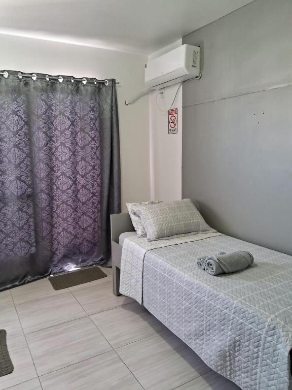 a bedroom with a bed and a purple curtain at Studio em São José SC in São José