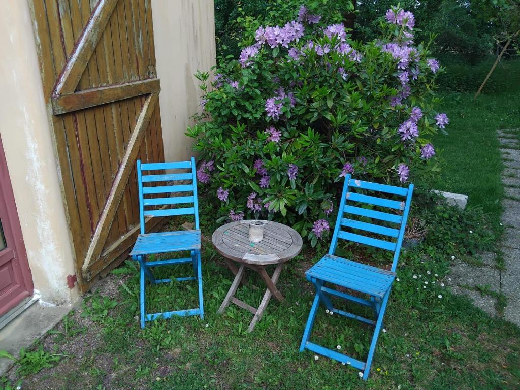 two blue chairs and a table next to a fence at La Bouvardière, gîte au calme, en pleine campagne, tout près de Rennes in Le Rheu