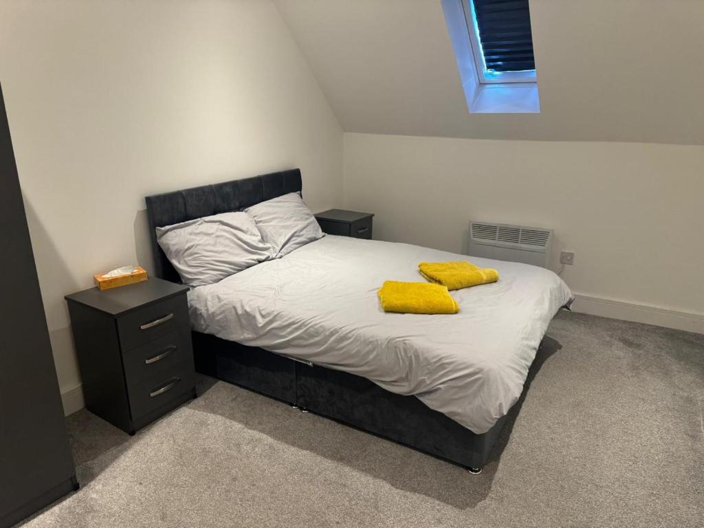 a bedroom with a bed with two yellow towels on it at Epsom High Street Apartment 9 in Epsom