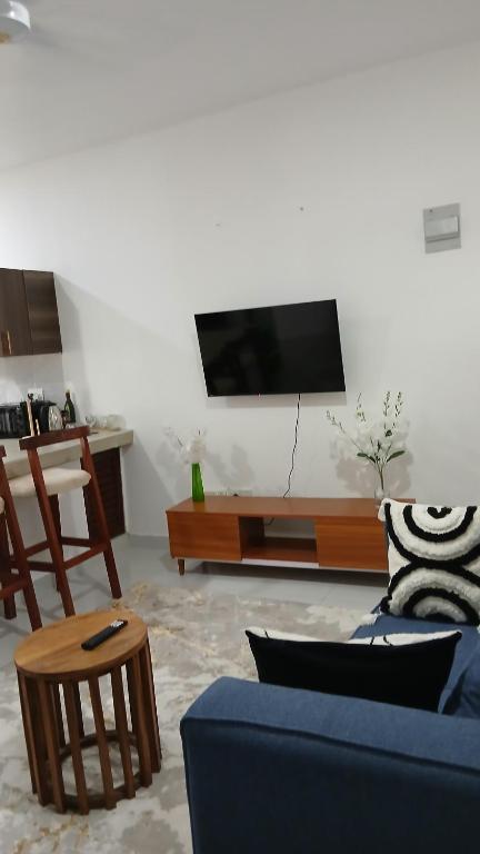 a living room with a couch and a tv on a wall at Imani staycations Diani 2 in Diani Beach