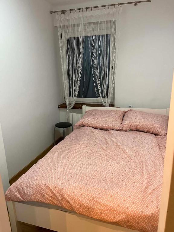 a bedroom with a bed with a pink comforter and a window at Piter Piotr Bezpalko in Knurów
