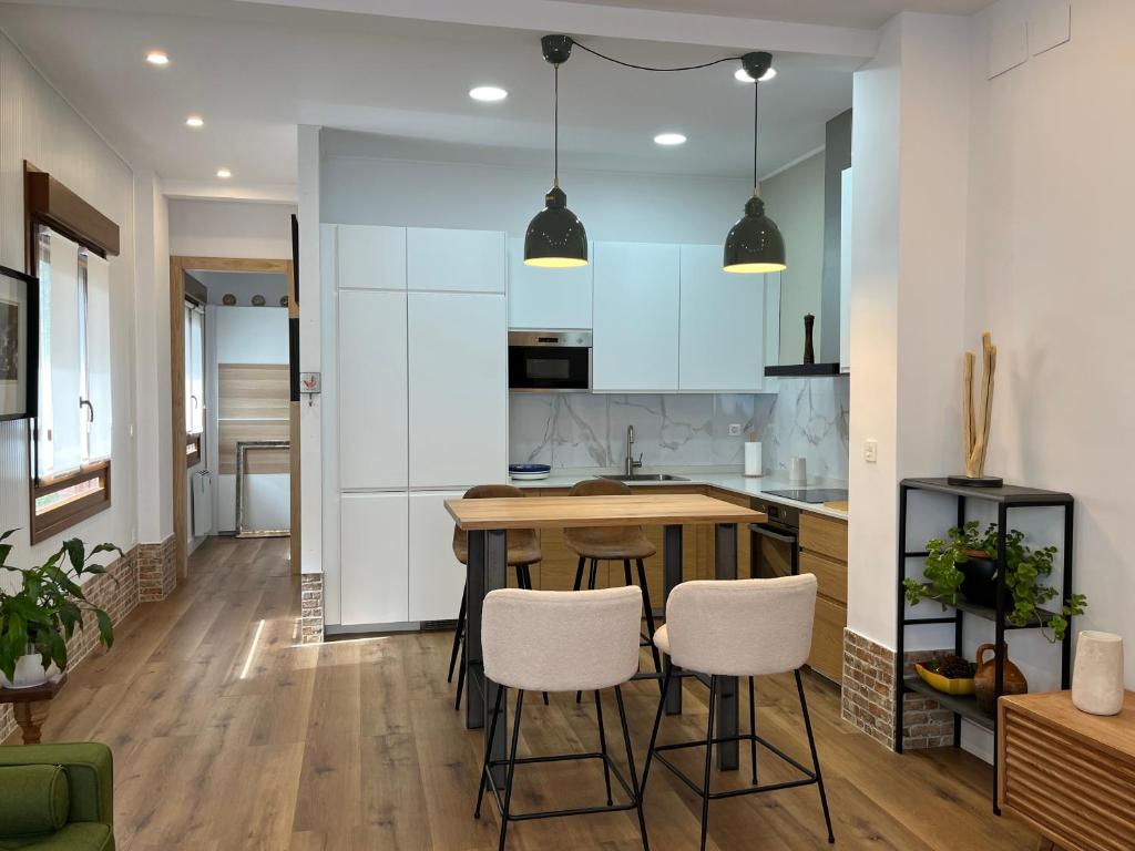 a kitchen with a wooden table and white stools at Tentietxea in Areatza