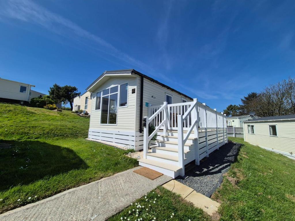 a small white house with a staircase in a yard at Joesphine Newquay Bay 37 in Newquay Bay Resort