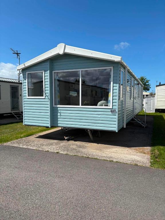 a blue mobile home sitting on the side of a road at Surf Shack Caravan - Lyons Winkups in Kinmel Bay