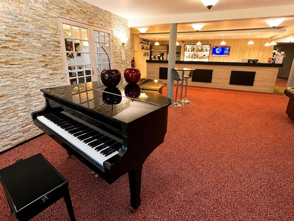 ein Klavier mit Vasen darauf in einem Zimmer in der Unterkunft Logis Hotel Altina in Pacy-sur-Eure