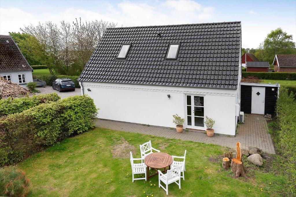 a white house with a table and chairs in a yard at 20430-Samso-Ballenvej-34A in Ballen
