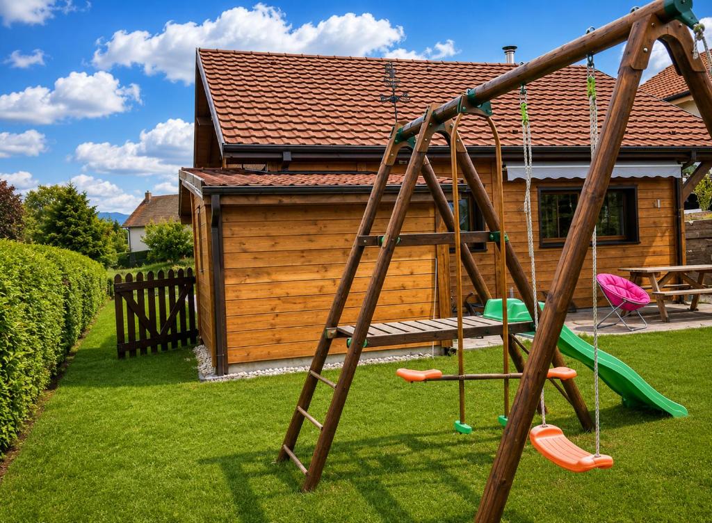 a playground in front of a wooden house at Gite châlet nature haute vosges in Anould