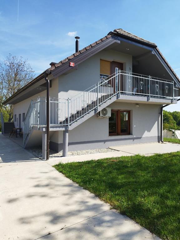 a white house with a balcony and a staircase at Apartmani Bele breze in Adlešiči