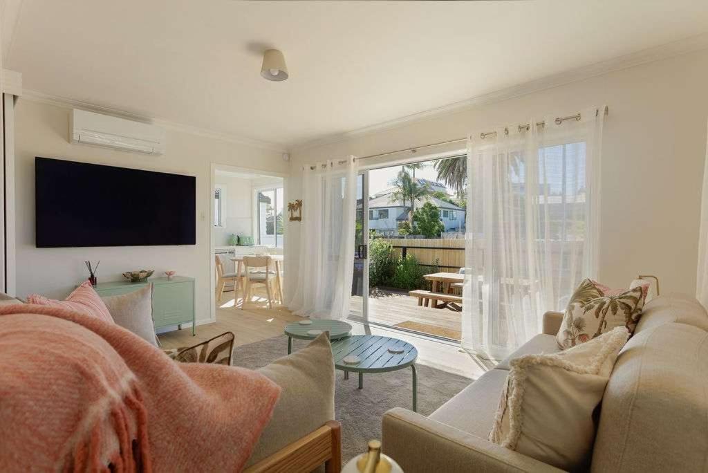 a living room with a couch and a tv at The Sun Deck Five Star Focused Downtown Location in Mount Maunganui