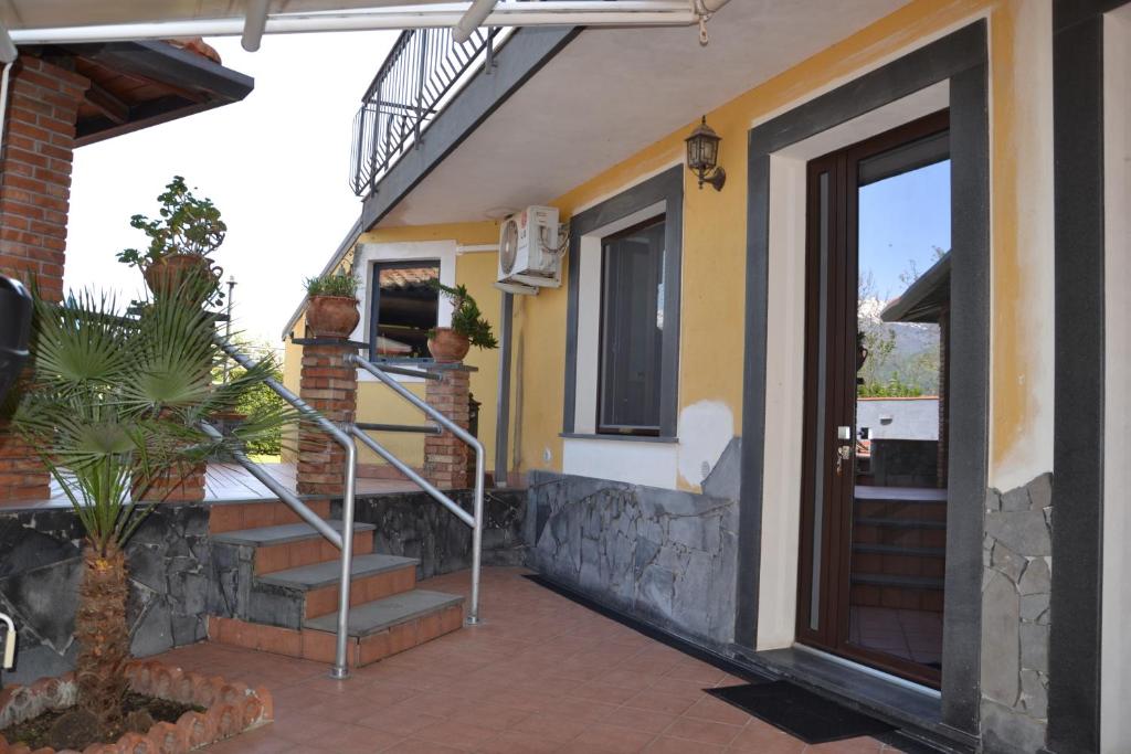 a house with a staircase next to a door at Casa RUDOM in Aci SantʼAntonio