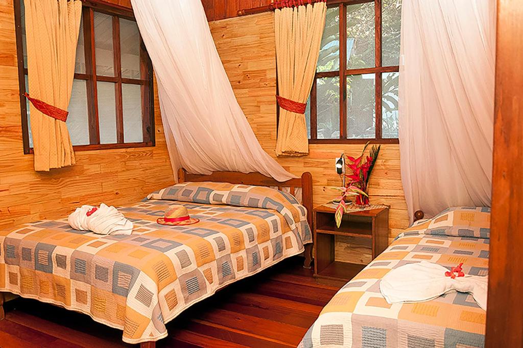 2 camas en una habitación con paredes y ventanas de madera en Pirate Cove, en Drake