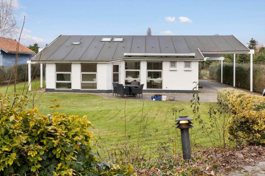 a white house with a black roof in a yard at 84265-Ega-Strandvangsvej-27 in Skæring