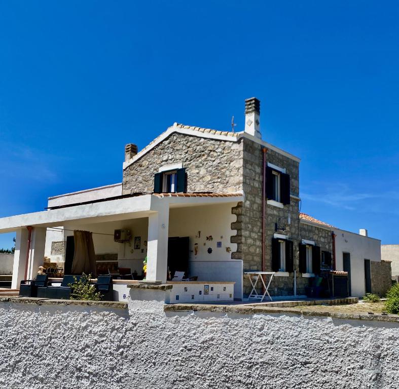 a stone house with a roof on a stone driveway at Sweet Home Spalmatore in Carloforte