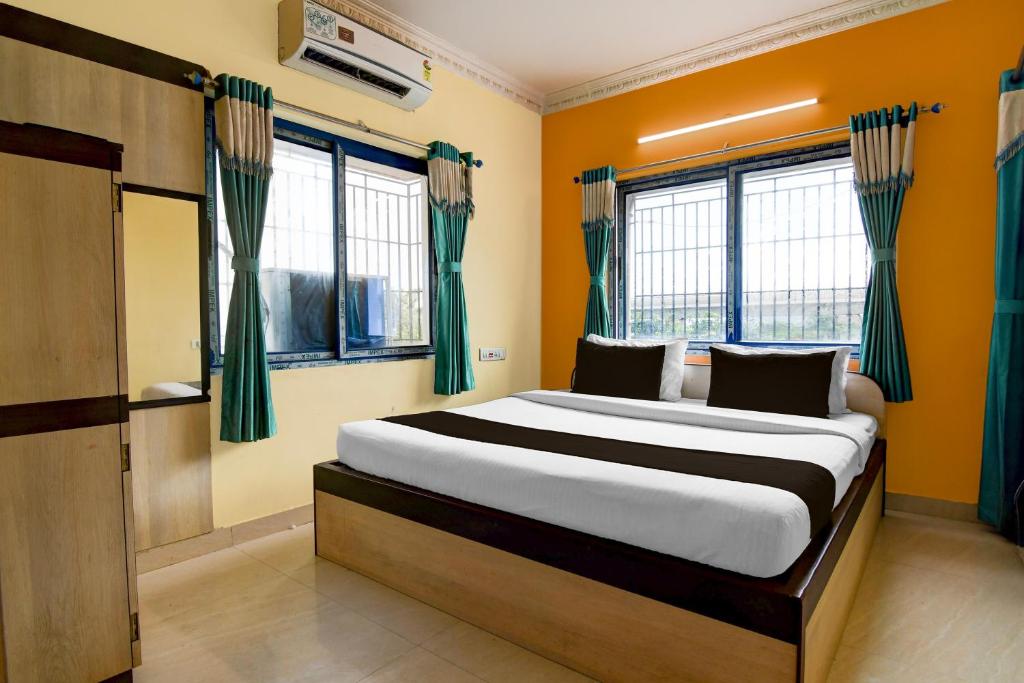 a bedroom with a large bed with green curtains at Hotel O Shyam sundar Hotel in kolkata
