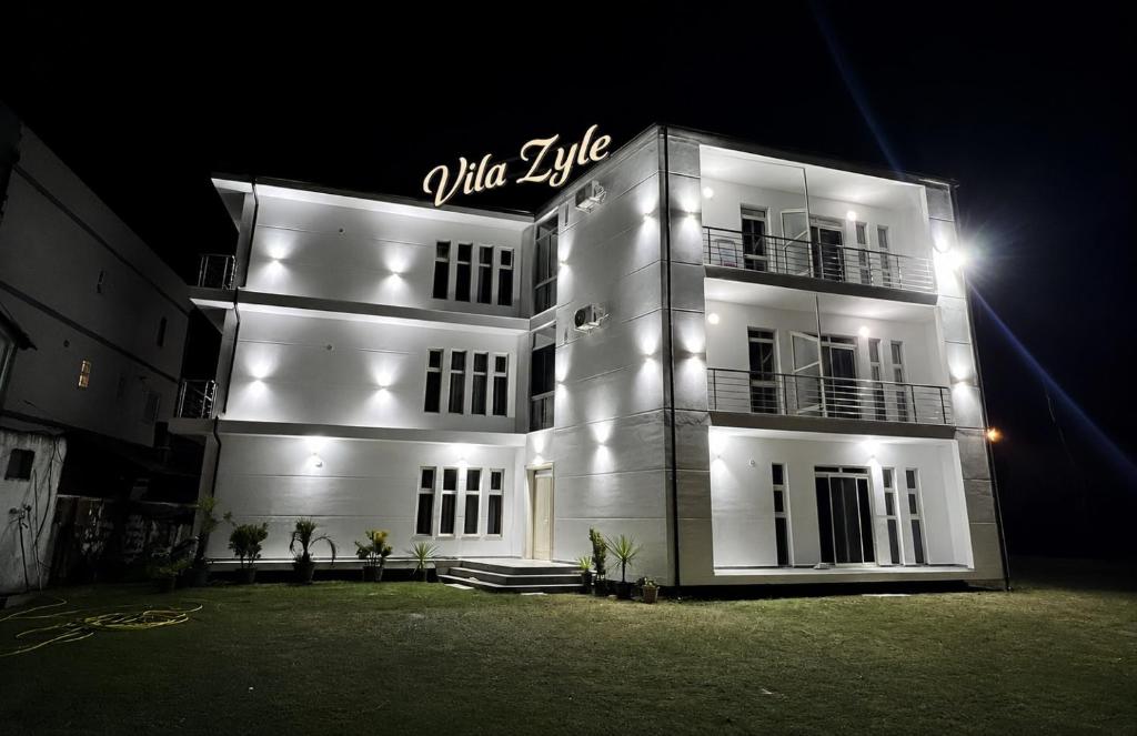 a white building with a sign on it at night at Vila Zyle in Velipojë
