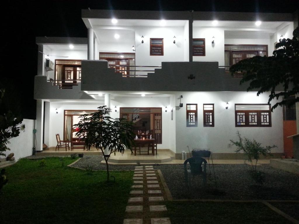 a white house at night with the lights on at Villa River View in Aluthgama