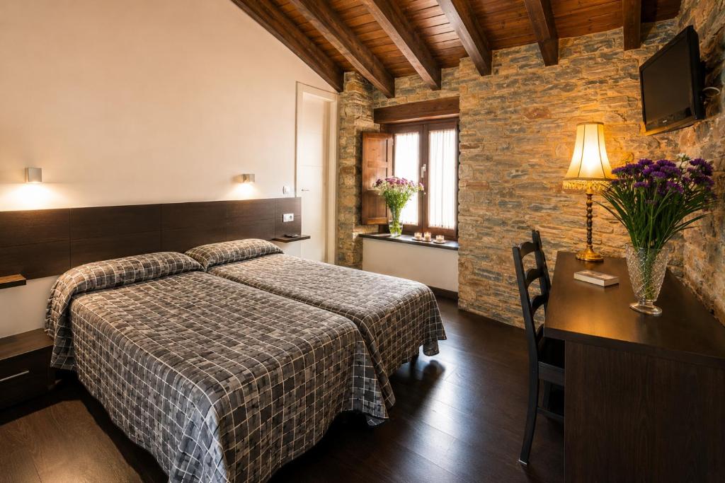 a hotel room with a bed and a table and a desk at Hostal Ultreia in Villafranca del Bierzo