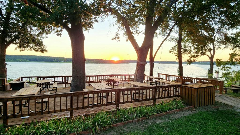 a wooden deck with tables and benches on the water at Lee's Grand Lake Resort Cabin 4 in Grove