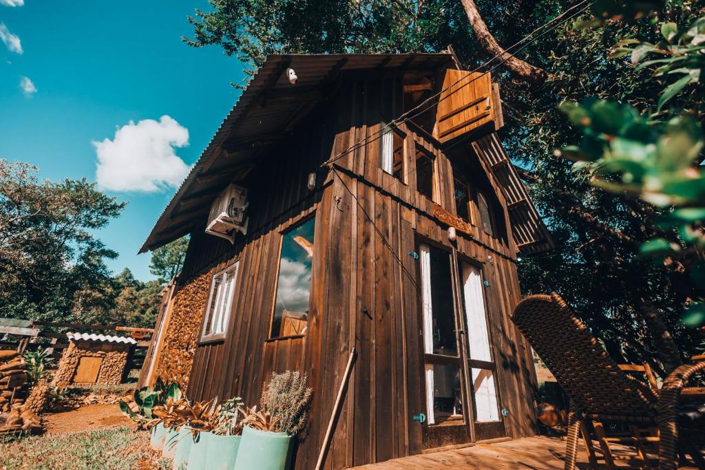 a small wooden cabin with windows in a yard at Chalé dos Alves in Morro Azul