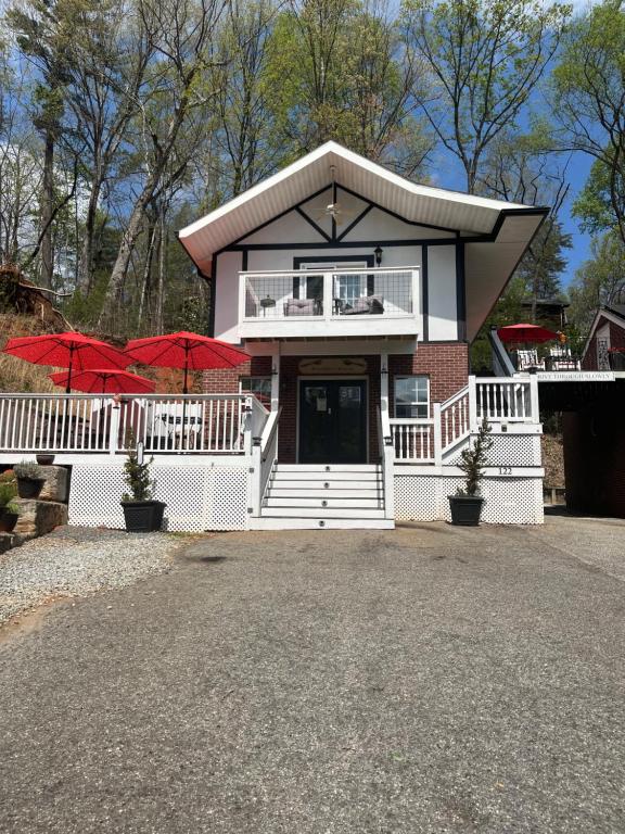 a white house with red umbrellas in front of it at Grafton Lodge in Lake Lure