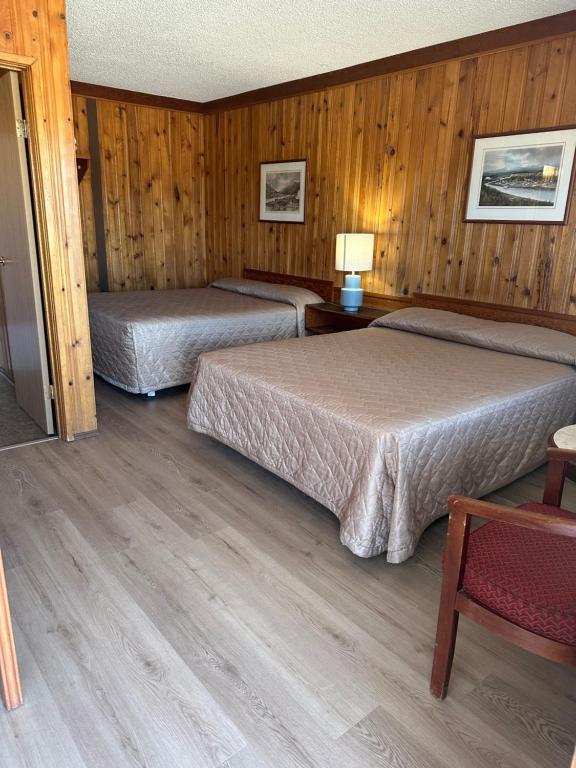 two beds in a room with wooden walls at Glacier View Inn in Haines Junction