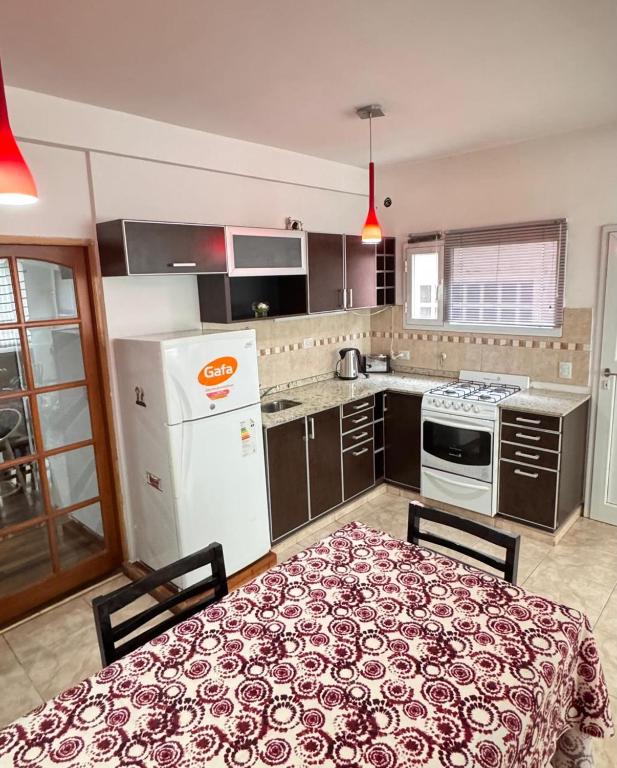 a kitchen with a table and a white refrigerator at Barrio Parque Residence in Caleta Olivia