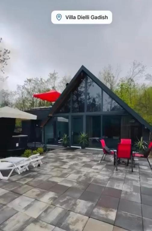 a house with a patio and red chairs at Villa Dielli Gadish in Gnjilane