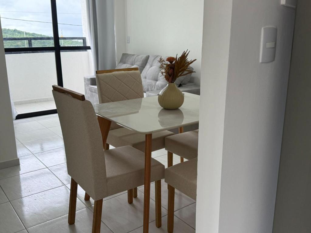 a dining room table with chairs and a vase with flowers at RESIDENCIAL MORADA DO VALE 03b in Garanhuns