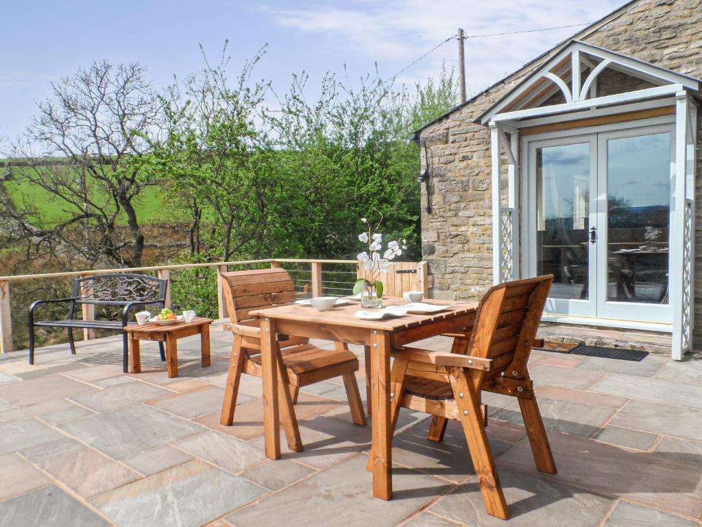 a wooden table and chairs on the patio of a cottage at Dewsnap Spring- Rtt4 in Chinley