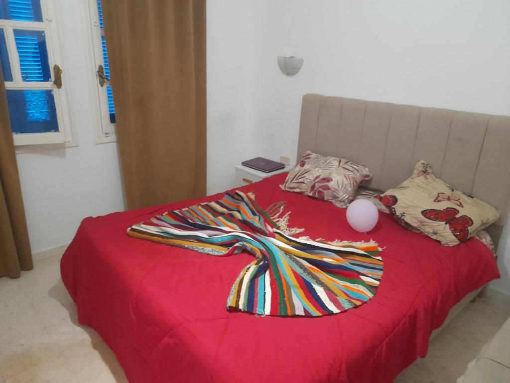 a red bed with a dress on top of it at Taguermess Tag 6 in Midoun
