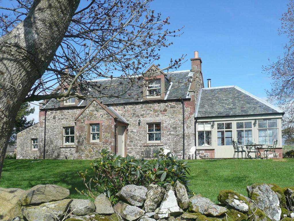 an old stone house with a stone wall at Clochridgestone Cottage in Aberargie