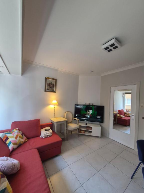 a living room with a red couch and a tv at Appartement Esmeralda in Knokke-Heist