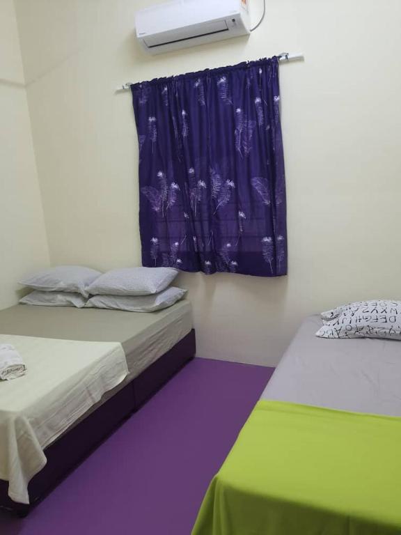 a room with two beds and a window with a curtain at Lavender 8B Homestay in TanjongMalim