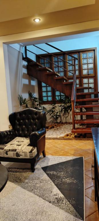 a living room with a leather couch and a staircase at Terraco Urbano Quarto Berlim in Sao Jose do Rio Preto