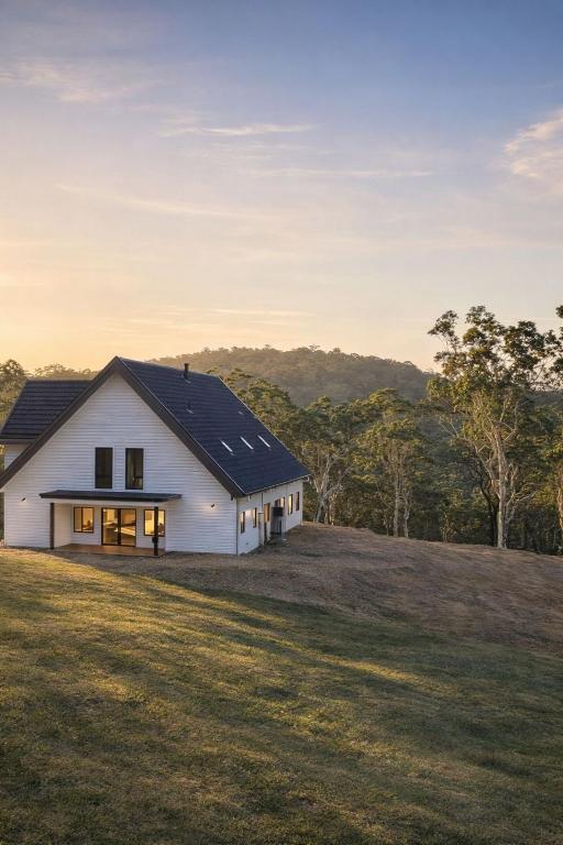 a white house with a black roof on a grass field at Redhill Batemans Bay in Batemans Bay
