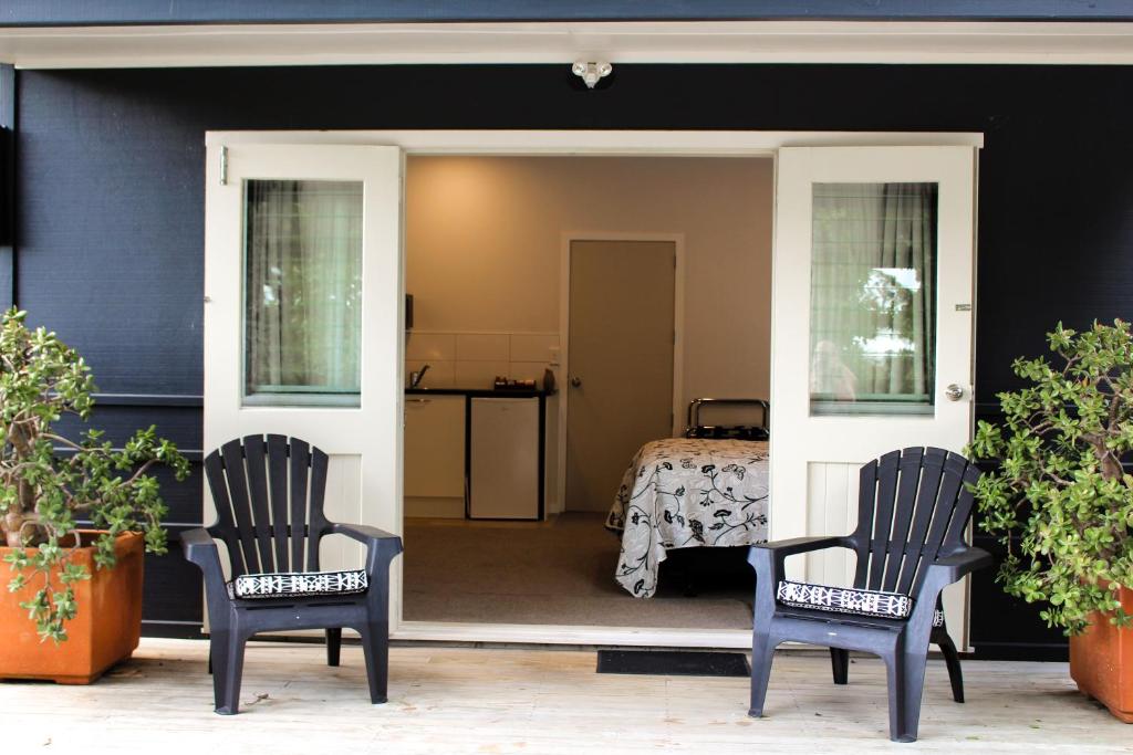 2 sillas sentadas en un porche con 1 dormitorio en Amazing Kiwi Lodge, en Whangamata