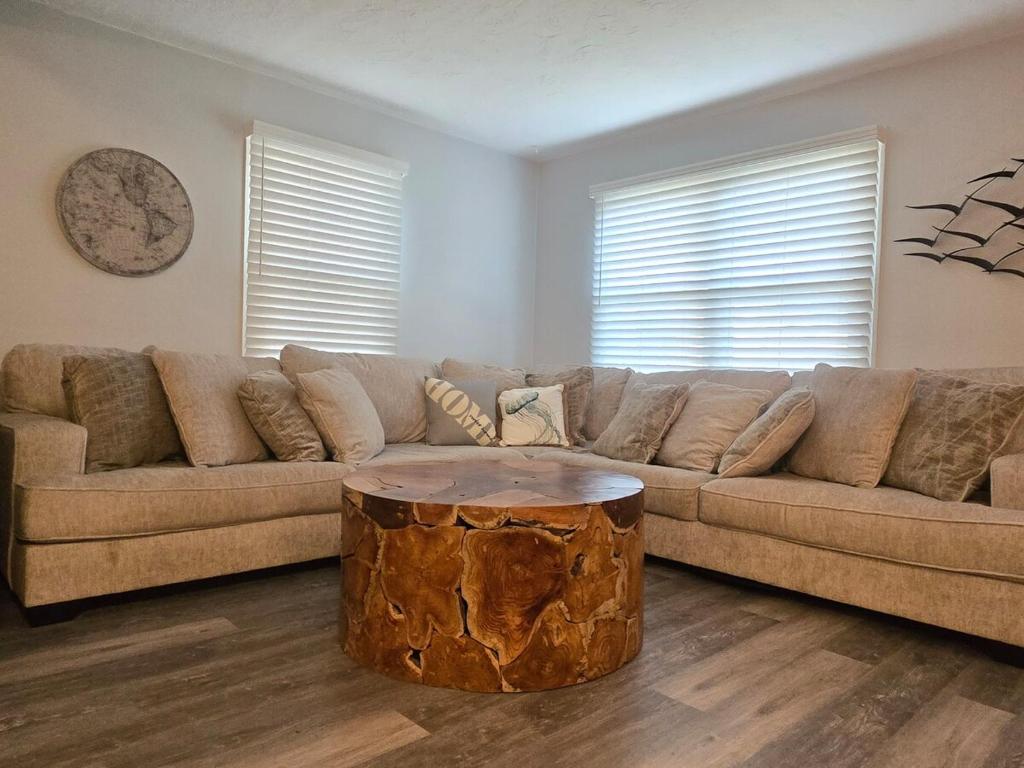 a living room with a large couch with a tree stump coffee table at 2BR House Perfect for Olympic NP Adventures in Port Angeles