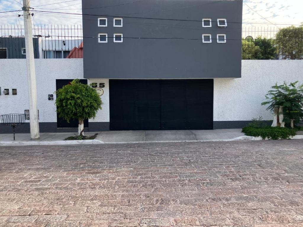 a white building with a black door and two trees at Residencia Sofía in Casa Blanca La Corregidora