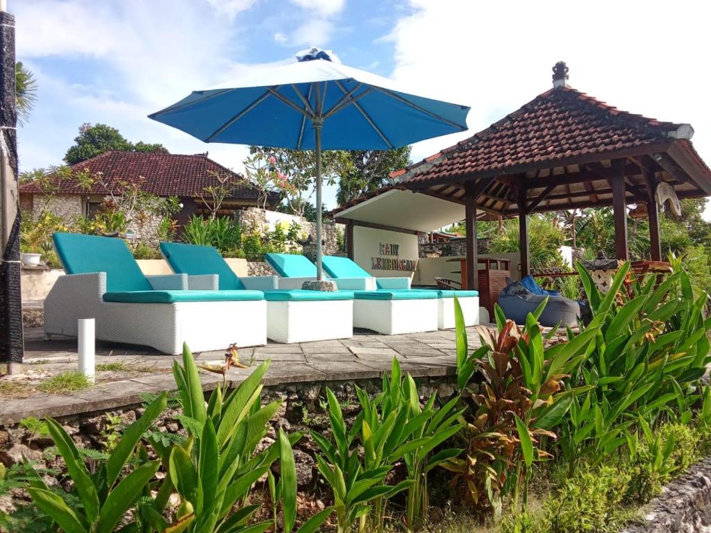 a patio with blue and white chairs and an umbrella at Rady Lembongan in Nusa Lembongan