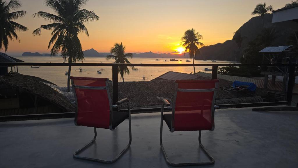 two red chairs sitting on a patio with a view of the ocean at YOLINDA's TOURIST INN in El Nido