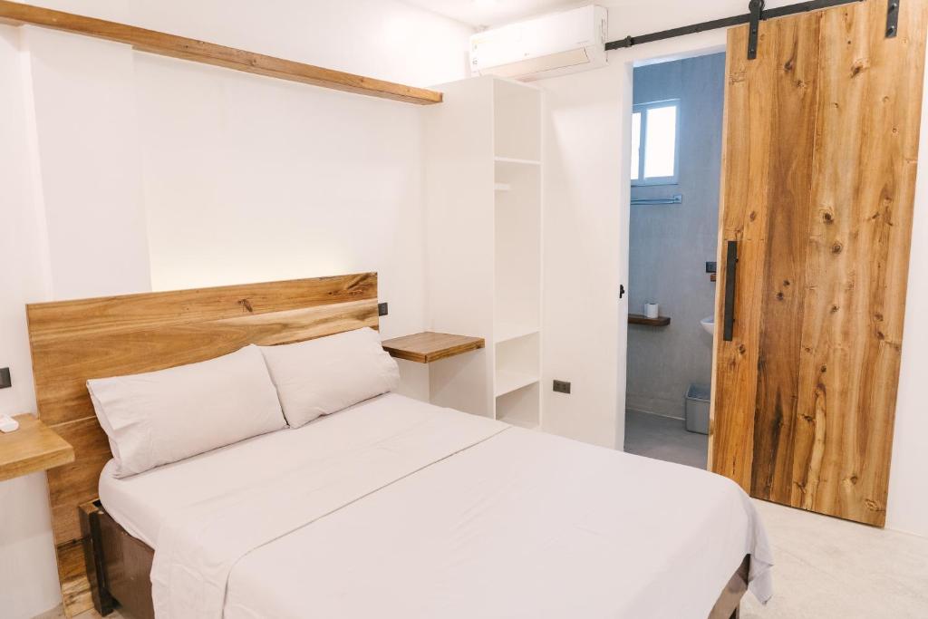 a bedroom with a white bed and a wooden headboard at Villa Gumamela Siargao in Catangnan