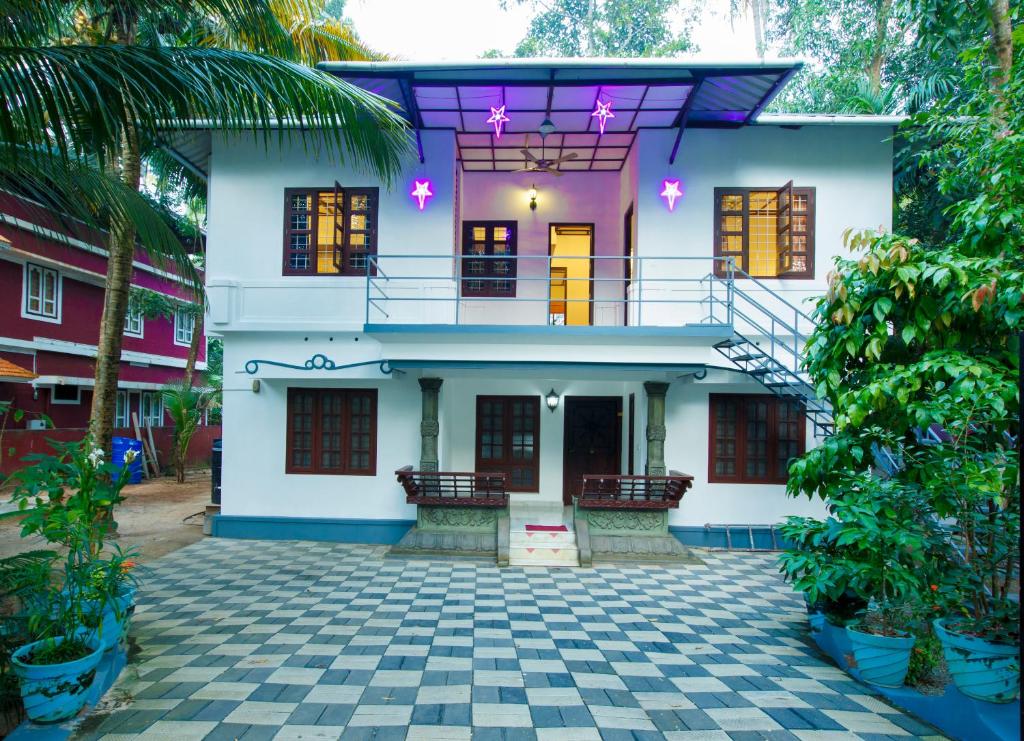 Casa blanca con balcón y patio en Marari White Home, en Alleppey