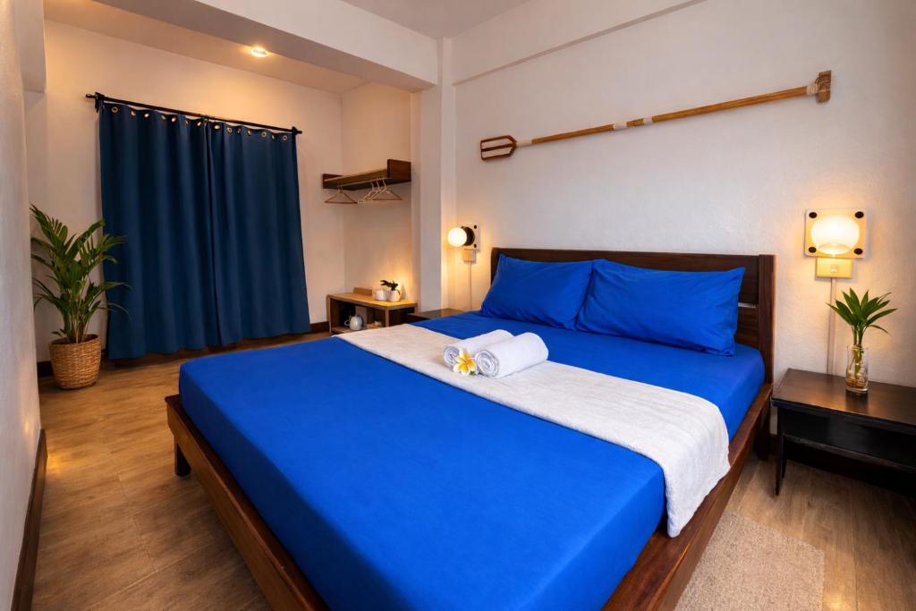 a bedroom with a blue bed and a blue curtain at Island Lyfe Adventures Hotel - 5 Minutes from El Nido Airport & Lio Beach in El Nido