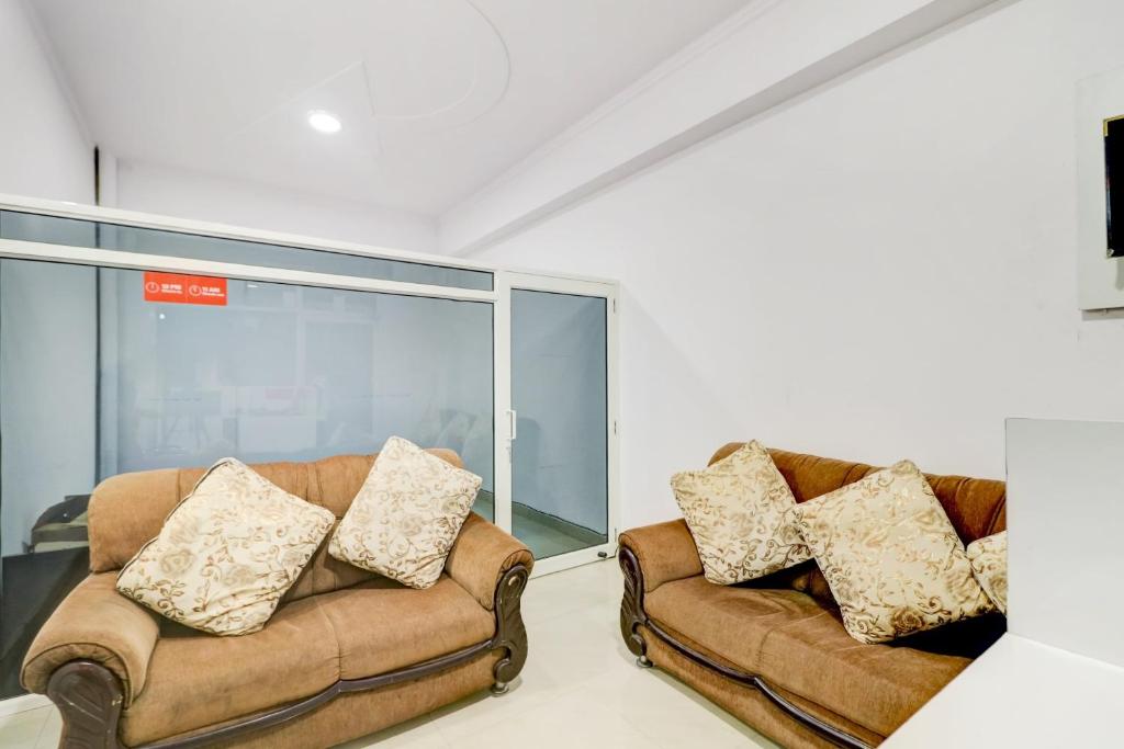 two brown leather couches in a room with a window at Hotel O Ratan Pacific Hotel And Party Hall in Ghaziabad