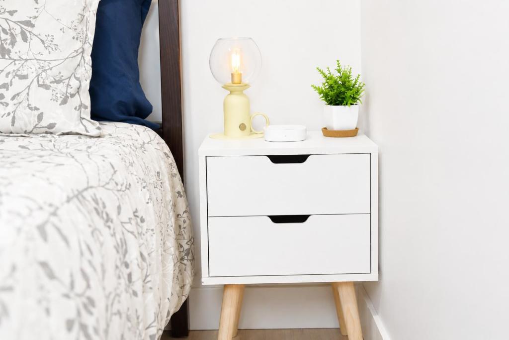 a white bedside table next to a bed at Centrally Located Modern Suite in North Vancouver