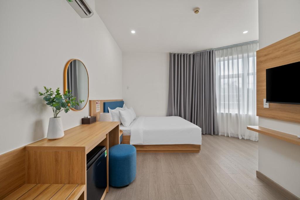 a hotel room with a bed and a television at Vorya Hotel Danang Beach in Danang