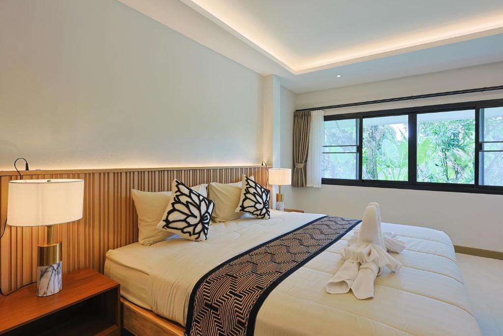 a bedroom with a large bed with pillows and a window at Bang Po Hut Nature - Lush Garden & Natural View in Ban Bang Po