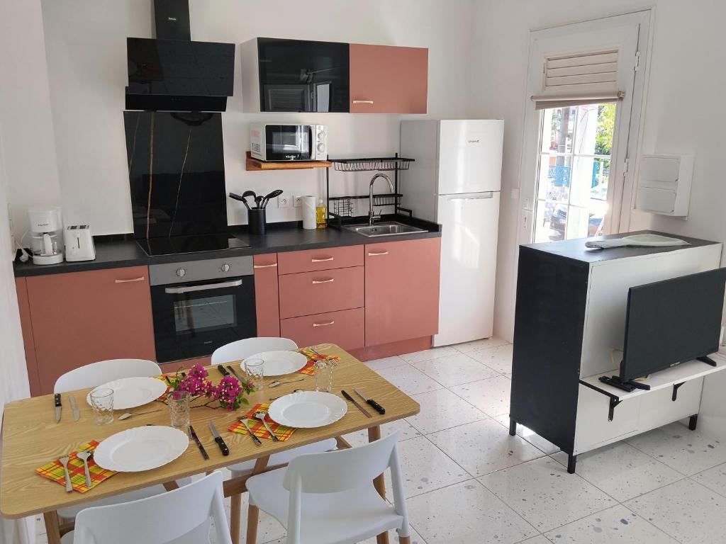 a kitchen with a wooden table with white chairs at Kaza LYBS in Fort-de-France
