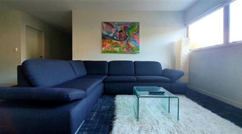 a living room with a blue couch and a table at 111 3rd Avenue Tauranga in Tauranga