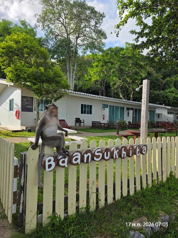 a monkey sitting on a fence in front of a house at Baansukhita in Laem Sing